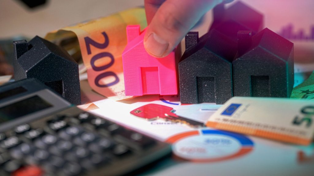 Casa miniatura sobre billetes y calculadora, representando el cálculo del precio de arriendo