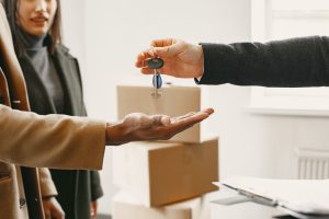 Entrega de llaves de un nuevo hogar junto a cajas de mudanza